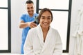 Latin man and woman wearing physiotherapy uniform massaging neck using percussion gun at beauty center Royalty Free Stock Photo