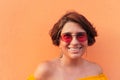 Latin mature woman with yellow blouse and sunglasses on orange background