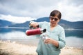 Latin Middle-aged Woman Enjoying Nature and Breakfast with Yerba Mate by Mountain Lake in Patagonia. Copy space