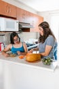 Latin mom slicing fruit with her teenage daughter with down syndrome in the kitchen, in disability concept in Latin America