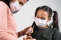 Latin mother applies disinfectant to her daughter to prevent infection, the two girls wear a protective mask. Infection