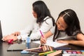 Latin mother and daughter working at home. Little girl doing homework on the desk while her mother work at home with the laptop Royalty Free Stock Photo