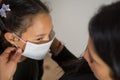 Latin mother puts the mask on her daughter, worried face tries to prevent the spread. Hygiene and safety concept. Concept of fear