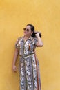 Oman posing in front of a yellow background wearing a dress