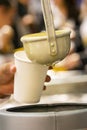 Latin person serving hot corn atol, typical guatemala drink, made with yellow corn, hot drink in disposable cup