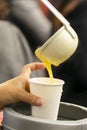 Latin person serving hot corn atol, typical guatemala drink, made with yellow corn, hot drink in disposable cup