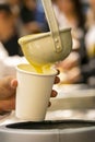 Latin person serving hot corn atol, typical guatemala drink, made with yellow corn, hot drink in disposable cup