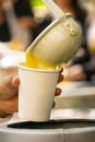 Latin person serving hot corn atol, typical guatemala drink, made with yellow corn, hot drink in disposable cup