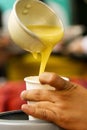 Latin person serving hot corn atol, typical guatemala drink, made with yellow corn, hot drink in disposable cup