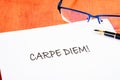 The Latin phrase Carpe Diem, a quote from Horace, means seize the moment. Live in the present written on a white piece of paper on Royalty Free Stock Photo