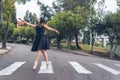 Latin teenage dancer girl with black dress walking elegantly with ballet shoes on a pedestrian crossing in the street Royalty Free Stock Photo