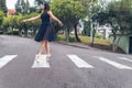 Latin teenage dancer girl with black dress walking elegantly with ballet shoes on a pedestrian crossing in the street