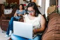 Latin teenage girl with down syndrome studying on computer sitting on sofa with her mom at home, in disability concept in Latin Royalty Free Stock Photo