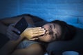 Latin woman on bed late at night texting using mobile phone yawning sleepy and tired