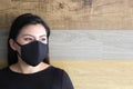 Latin woman with black protective mask and colorful wall in the background, new normal covid-19