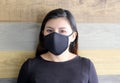 Latin woman with black protective mask and colorful wall in the background, new normal covid-19