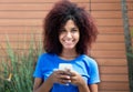 Latin woman in blue shirt sending message with phone Royalty Free Stock Photo