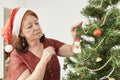 Latin woman decorating a Christmas tree hanging a snowman ornament on a branch Royalty Free Stock Photo