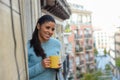 Latin woman drinking cup of coffee or tea smiling happy at apartment window balcony Royalty Free Stock Photo