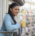 Latin woman drinking cup of coffee or tea smiling happy at apartment window balcony Royalty Free Stock Photo