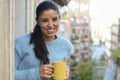 Latin woman drinking cup of coffee or tea smiling happy at apartment window balcony Royalty Free Stock Photo