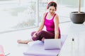 Latin woman with headphones watching online yoga videos sitting on the mat at home in Latin America Royalty Free Stock Photo