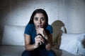 Latin woman at home sofa couch in living room watching television scary horror movie or suspense thriller Royalty Free Stock Photo