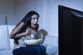 Latin woman at home sofa couch in living room watching television scary horror movie or suspense thriller Royalty Free Stock Photo