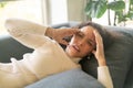 Latin woman lying down on sofa with headache feeling Royalty Free Stock Photo