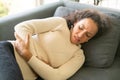 Latin woman lying down on sofa with stomachache feeling Royalty Free Stock Photo