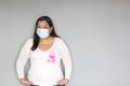 Latin woman with protection mask, black hair and white sweater with pink ribbon for campaign against breast cancer Royalty Free Stock Photo