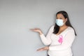 Latin woman with protection mask, black hair and white sweater with pink ribbon for campaign against breast cancer Royalty Free Stock Photo