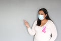 Latin woman with protection mask, black hair and white sweater with pink ribbon for campaign against breast cancer Royalty Free Stock Photo