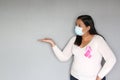 Latin woman with protection mask, black hair and white sweater with pink ribbon for campaign against breast cancer Royalty Free Stock Photo