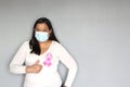 Latin woman with protection mask, black hair and white sweater with pink ribbon for campaign against breast cancer Royalty Free Stock Photo