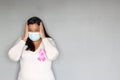 Latin woman with protection mask, black hair and white sweater with pink ribbon for campaign against breast cancer Royalty Free Stock Photo