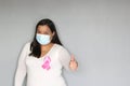Latin woman with protection mask, black hair and white sweater with pink ribbon for campaign against breast cancer Royalty Free Stock Photo