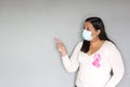 Latin woman with protection mask, black hair and white sweater with pink ribbon for campaign against breast cancer Royalty Free Stock Photo