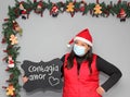Latin woman with santa claus hat and blackboard with message `contagious love` in Christmas decoration