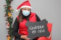 Latin woman with santa claus hat and blackboard with message `stay at home` in Christmas decoration
