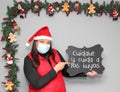 latin woman with santa claus hat and blackboard with message `take care and take care of yours` in Christmas decoration