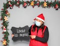 Latin woman with santa claus hat and blackboard with message `wash your hands` in Christmas decoration