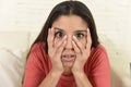 Latin woman sitting at home sofa couch in living room watching television scary horror movie Royalty Free Stock Photo