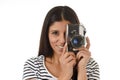 Latin woman taking pictures looking through the viewfinder of an old cool retro vintage photo camera