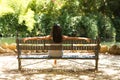 Latin woman, young and beautiful brunette relaxed and sitting on a bench looking at the pond and trees in the area. The photo is Royalty Free Stock Photo