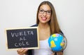 Latin young female teacher holding globe and blackboard with spanish written Royalty Free Stock Photo