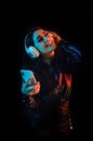 Latin young woman with headphones listening to music over color neon and black background in Mexico Latin America