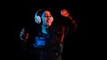 Latin young woman with headphones listening to music over color neon and black background in Mexico Latin America
