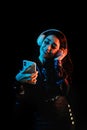 Latin young woman with headphones listening to music over color neon and black background in Mexico Latin America