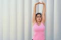 Latina athlete concentrating on stretching her arms while warming up her body during a workout in the park